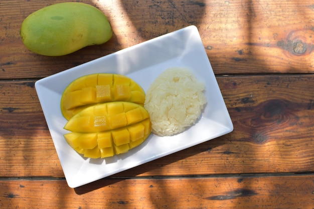 Foto vista dall'alto di una fetta di mango su un piatto bianco messo su una tavola di legno frutta per spuntino e sano