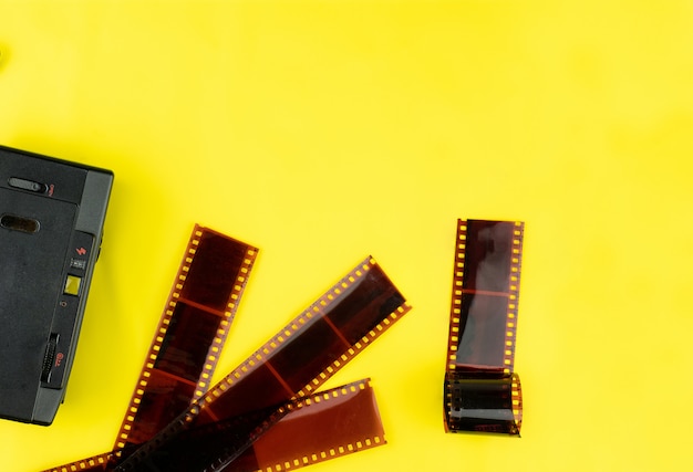 手動の古いカメラの平面図と黄色の背景でストリップするために使用されるフィルム