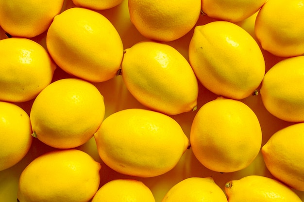 Фото Взгляд сверху много зрелых лимонов на желтой поверхности, предпосылке или концепции
