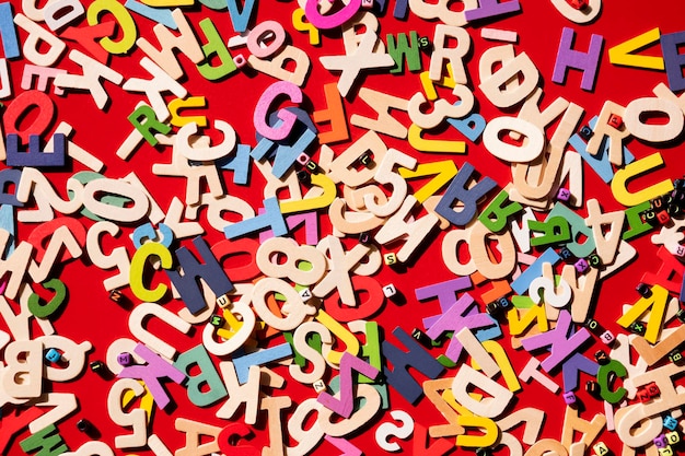 Top view of many wooden colorful alphabet with numbers on red tabletop