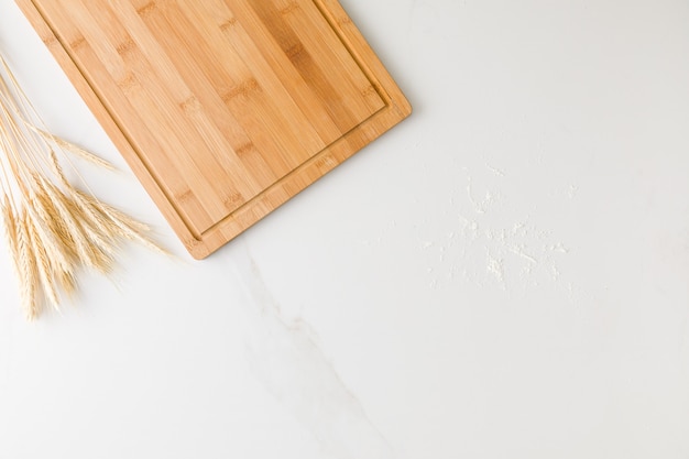 Photo top view of a marble table with a wooden board, wheat and flour with space for text