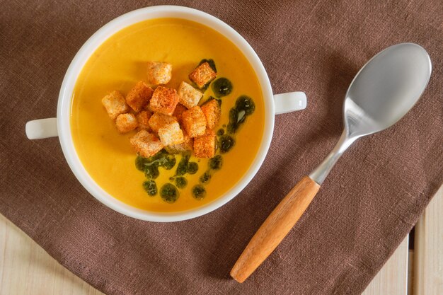 Top view of mashed peas soup with curry and crouton on wooden table