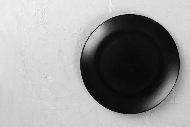 Top view of matte round empty black plate on grey cement