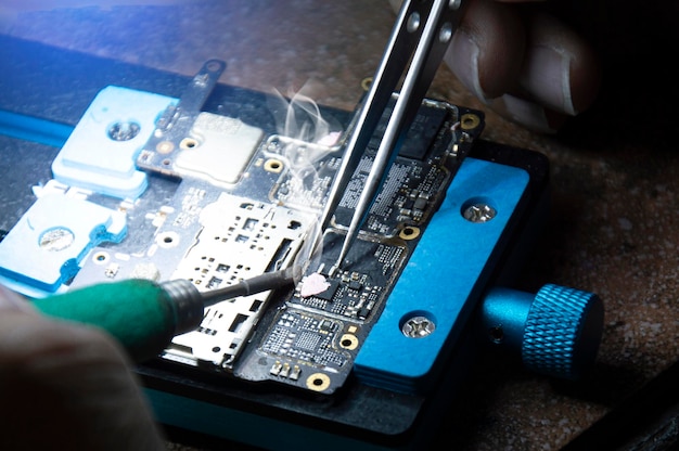 Фото Механик, выполняющий ремонт материнской платы смартфона, ремонт схемы смартфона