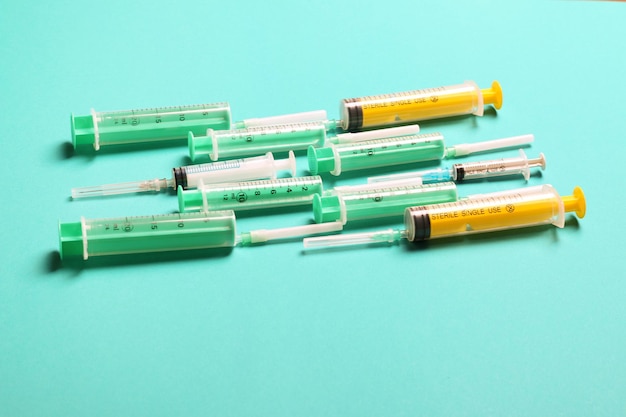 Top view of medical syringes with needles at blue background with copy space Injection treatment concept