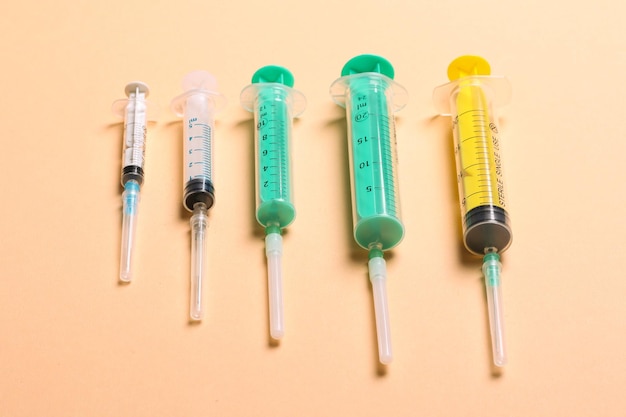 Top view of medical syringes with needles at orange background with copy space Injection treatment concept