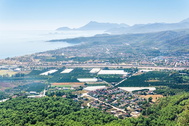 Top view of Mediterranean coastal resort village with orchards and hotels in Camyuva, Turkey