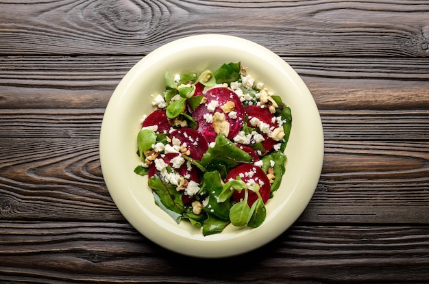 Top view at mediterranean roasted beet salad with walnuts feta cheese and mash leaves on wooden table