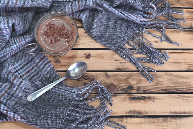 Top view on milk chocolate in a mug on scarf on wooden table