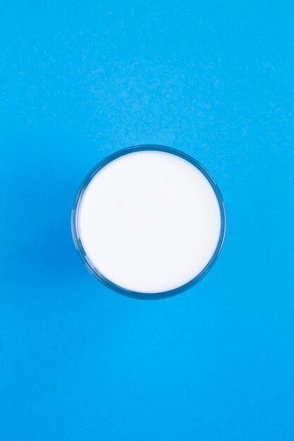 Top view of milk in a glass in the center of the blue background. location vertical