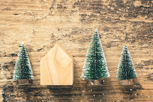 Top view of mini christmas tree wood home toy on rustic wooden table with snow fall