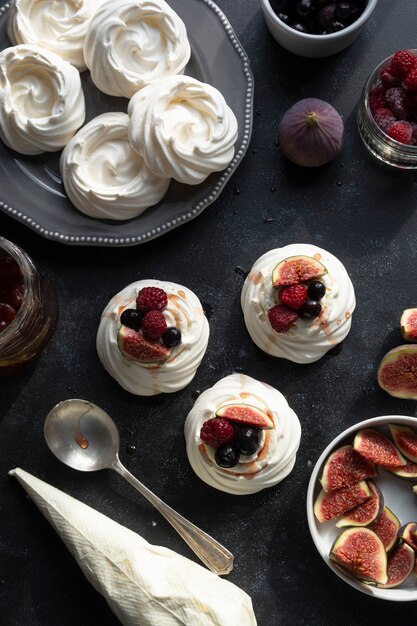 Photo top view of mini pavlova meringue cakes decorated with berries and figs