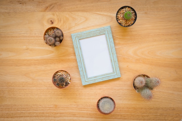 Top view of mix cactuses and blue photo frame on rustic wooden background with copy space