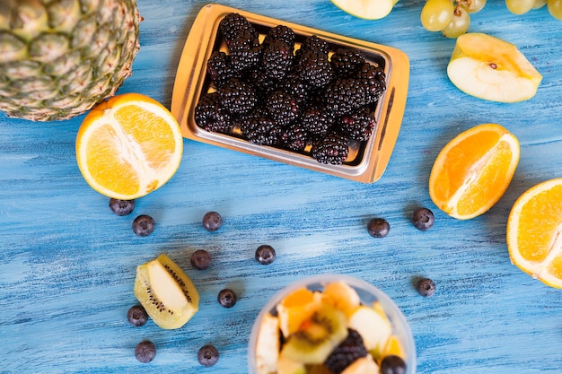 Top view of mixed exotic fruits over a blue table. Abundance of natural fruits