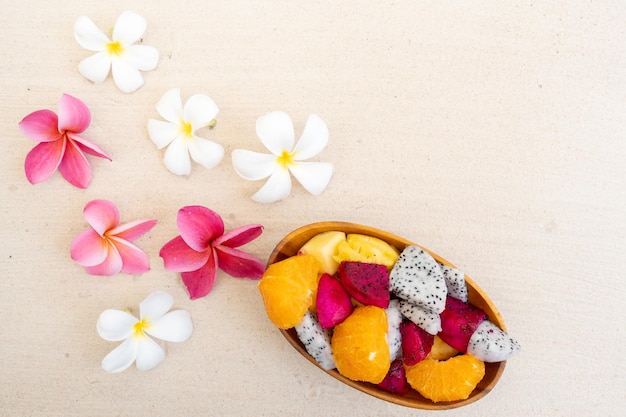 Top view Mixed Fresh Fruit in wooden bowl on Sand Beach Background.