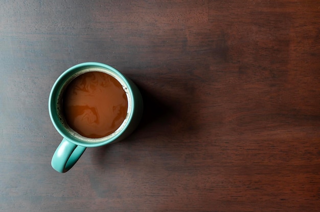 Top view mocha coffee in green cup on wooden table with copy space