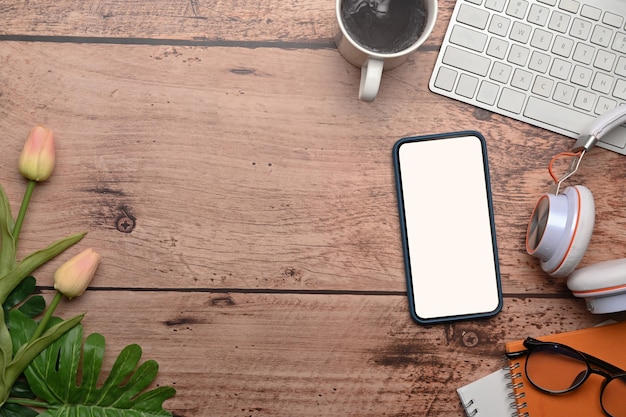 Top view of mock up mobile phone and laptop on wooden table.