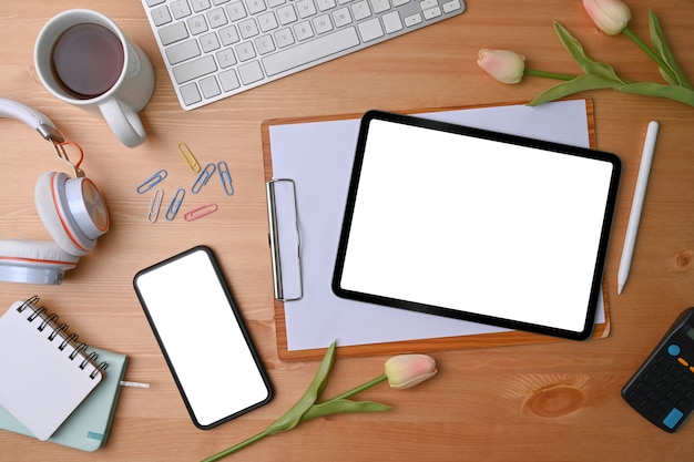 Top view mock up smart phone and digital tablet with blank screen on wooden desk.