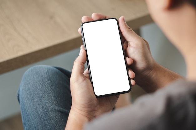 Top view Mockup image hand using a smartphone man Holding Cell Phone With Blank Screen