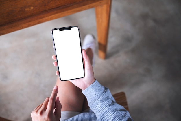 사진 빈 흰색 바탕 화면이 있는 휴대폰을 들고 있는 여성의 상위 뷰 모형 이미지