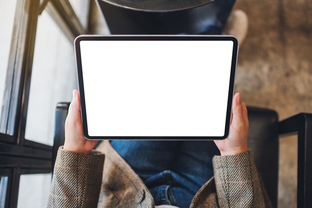 Immagine mockup vista dall'alto di una donna che tiene in mano un tablet pc nero con schermo bianco vuoto