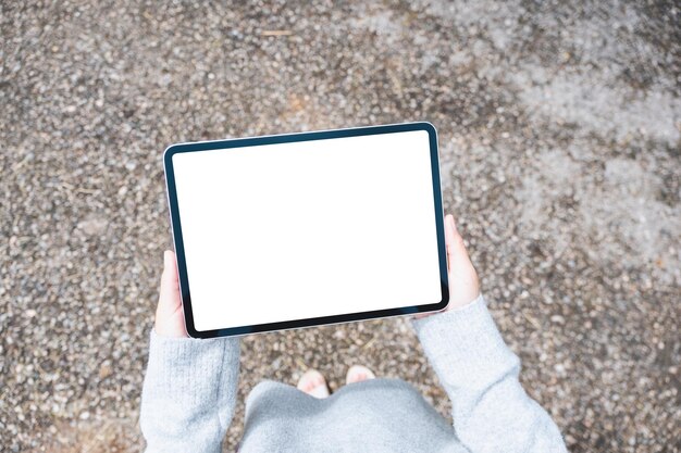 Top view mockup image of a woman holding digital tablet with blank white desktop screen in the outdoors