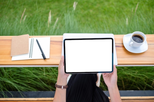 Top view mockup image of a woman holding digital tablet with blank white desktop screen in the outdoors