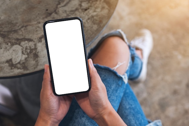 Top view mockup image of a woman holding mobile phone with blank white desktop screen