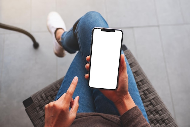 Top view mockup image of a woman holding mobile phone with blank white desktop screen