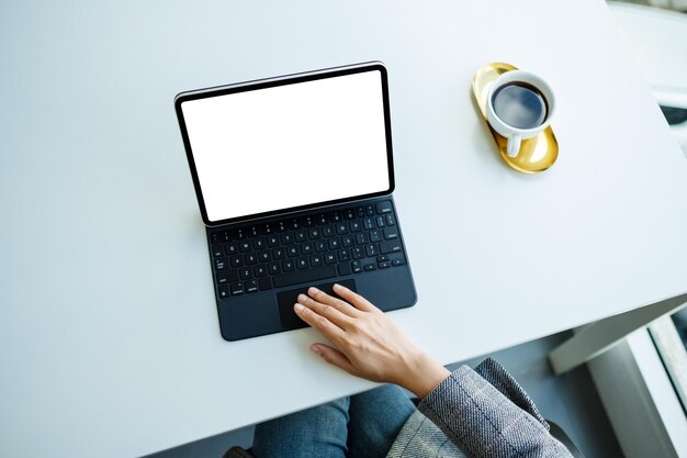 Immagine mockup vista dall'alto di una donna che utilizza e tocca il touchpad del tablet con schermo desktop bianco vuoto come un computer in ufficio