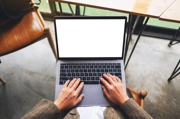 Top view mockup image of a woman using and typing on laptop computer with blank white desktop screen