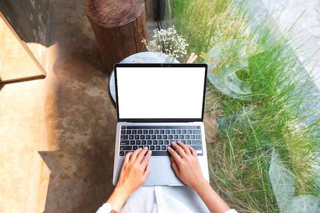 Top view mockup image of a woman using and typing on laptop computer with blank white desktop screen
