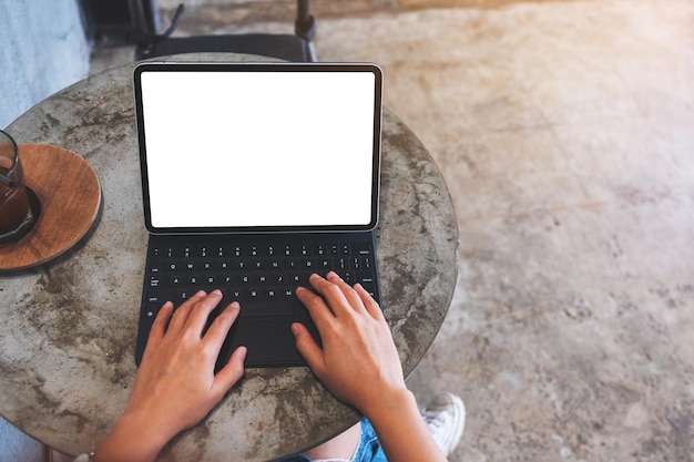 Top view mockup image of a woman using and typing on tablet keyboard with blank white desktop screen as a computer pc on the table