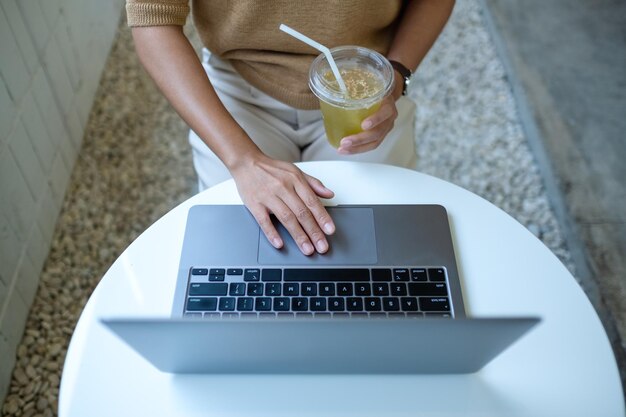 Top view mockup image of a woman working and touching on laptop touchpad in cafe