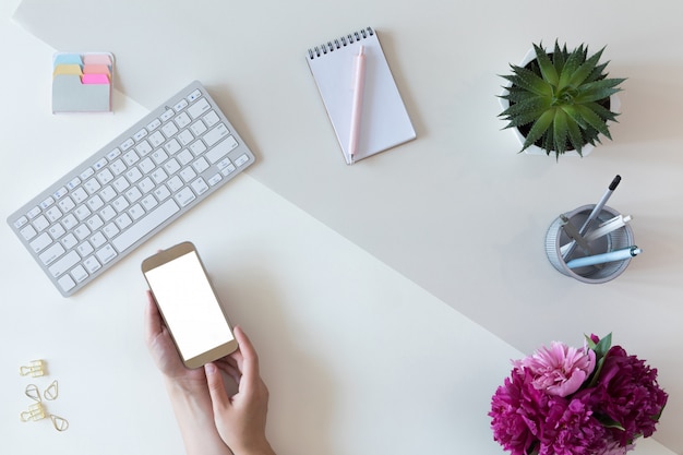 Top view of mockup of mobile phone with white copy space screen, flat lay, female workspace concept for woman office desk