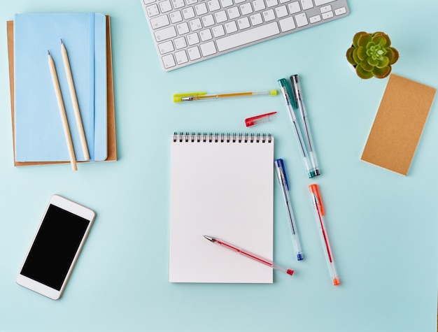 Top view modern blue office desktop with blank notepad