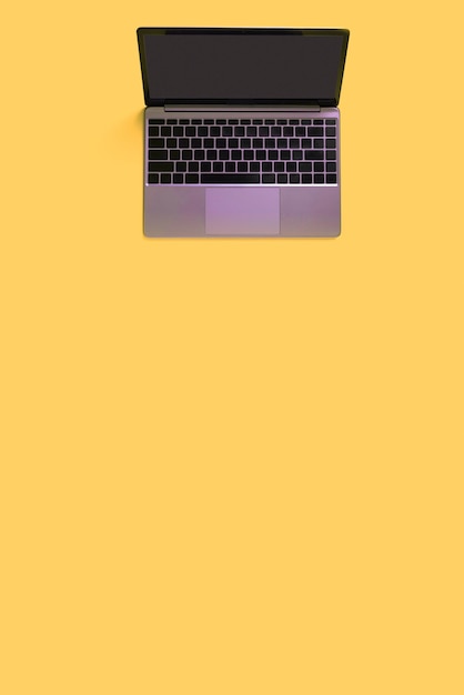 Top view of modern laptop isolated on yellow background Copy space