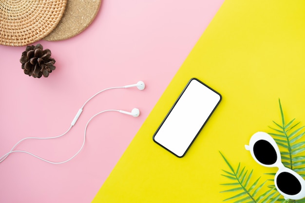 Top view of modern smartphone and white headphones on yellow with pink color background