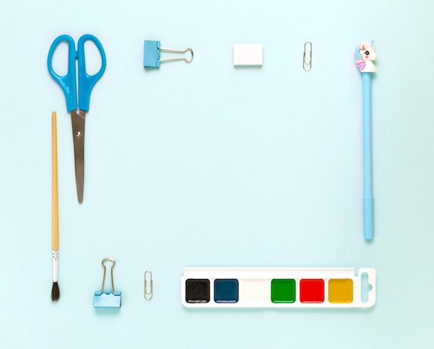 Top view of modern white blue office desktop with school supplies and stationery on table around empty space for text Back to school concept flat lay with mockup