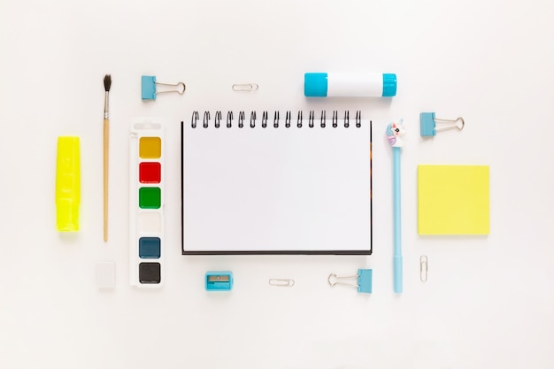 Photo top view of modern white, blue, yellow office desktop with school supplies and stationery on table around empty space for text. back to school concept flat lay with mockup
