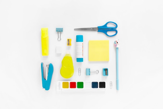 Top view of modern white blue yellow office desktop with school supplies and stationery on table around empty space for text Back to school concept flat lay with mockup