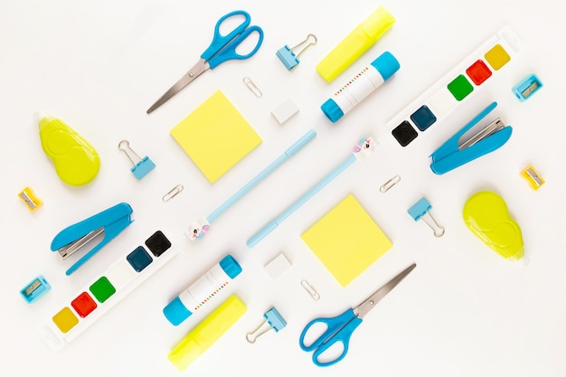 Top view of modern white, blue, yellow office desktop with school supplies and stationery on table