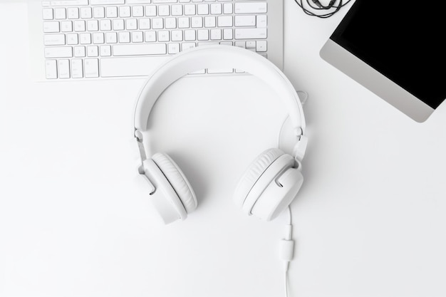 Top view of modern white desk with Headset and computer keyboard on white background