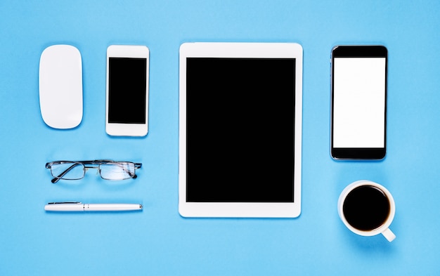 Top view, Modern workplace with laptop and tablet with smart phone placed on a pastel yellow background. Copy space suitable for use in graphics.