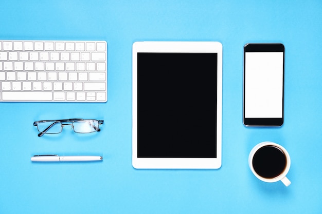 Vista dall'alto, moderno ambiente di lavoro con tablet con smart phone collocato su uno sfondo blu pastello