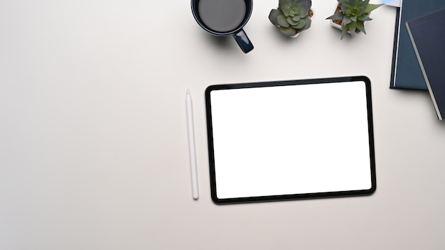 Top view of modern workspace with mock up digital tablet with blank screen and equipment on white table.