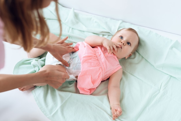 Top view. Mom giving baby diaper change at home.