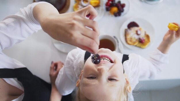 Top view of mom and her little girl drinks tea and eats cherry