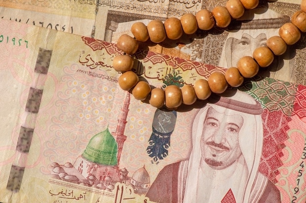 Top view of money, banknote and coin of Saudi Arabia Riyals and prayer beads, in shallow focus