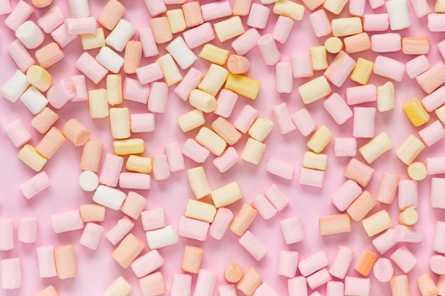 Photo top view on multi-colored marshmallows on a monochrome pink background